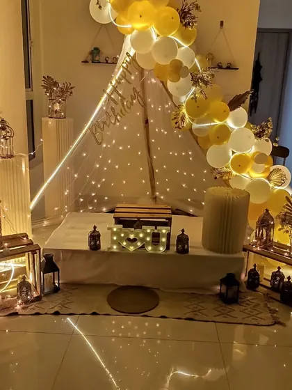 A full view of the elegant yellow and white cabana tent setup, showing the surrounding lanterns and decor pieces.