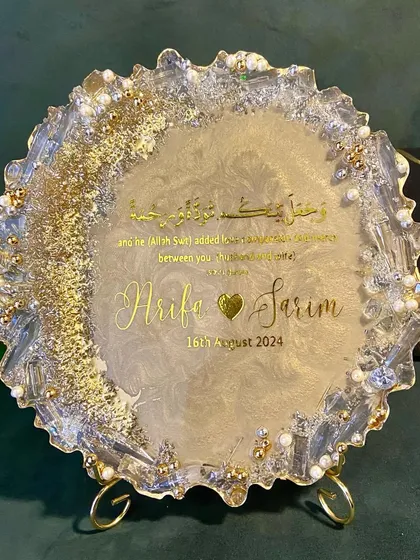 A beautiful resin engagement plaque designed to celebrate a new union. This piece features the couple's names, their special date, and a Quranic verse, all set in a shimmering gold and pearl design with a geode-style edge.