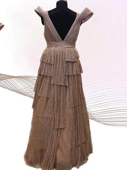 The full back view of the tiered rose gold gown, showcasing its dramatic silhouette and shimmering fabric.