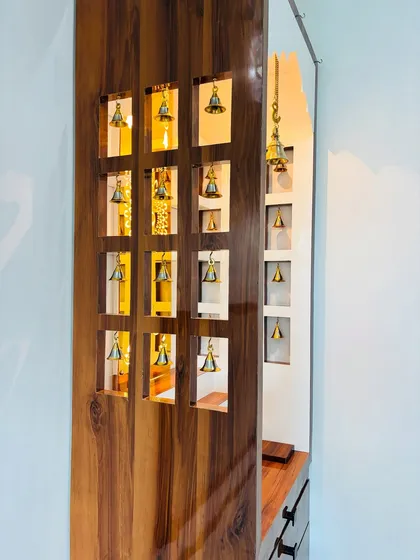 A detail shot of the mandir's side panel, where each cutout holds a small, real brass bell.