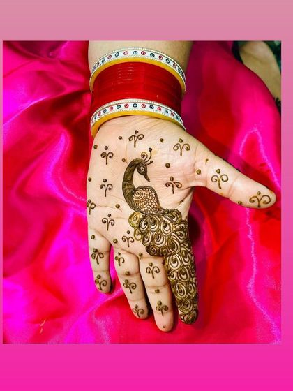 A minimalist peacock design on the back of the hand. A single, elegant peacock feather extends down the finger, surrounded by delicate dots for a simple yet beautiful look.