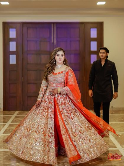 A gorgeous bride twirling in her orange and gold anarkali. This full-length shot captures the beautiful flare and movement of the outfit.