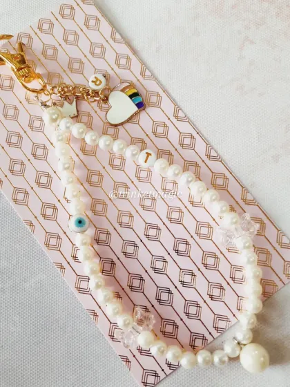 I love making your stories into something you can carry every day. This custom phone charm was made with love, featuring the owner's initial 'T', her daughter's initial 'R', a rainbow heart, and a protective evil eye, all tied together with elegant pearls.