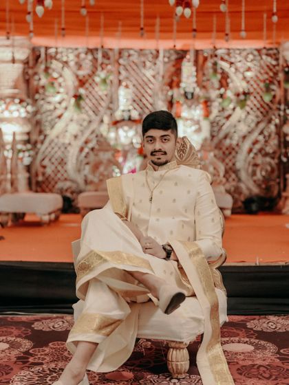 A confident groom posing on his wedding stage in traditional attire.