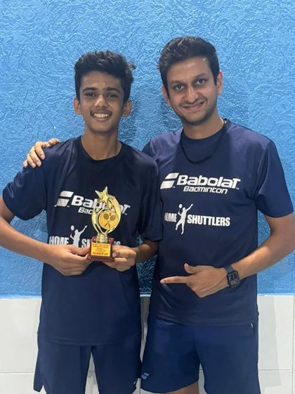 A student proudly displays his trophy while standing with his coach. This image reflects the personal guidance and mentorship we provide to our competitive players.