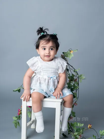 A more classic and serene portrait from the same session. The simple grey background and soft lighting create a timeless look, highlighting her sweet expression.
