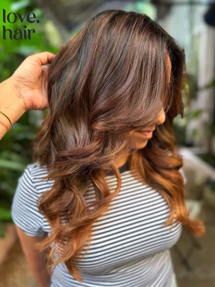 A close-up showing the soft, face-framing layers and the warm honey tones of this non-bleach balayage.