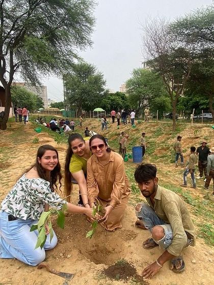 Three volunteers from Estee Advisors smile for the camera as they plant a tree with our team member, enjoying their day of giving back to nature.