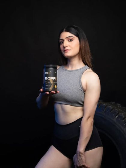 A strong, confident pose with the model holding the BCAA supplement. The direct eye contact and clear product presentation make this a compelling image for advertisements and promotional materials.