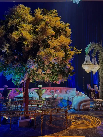 A dreamscape featuring glowing floral trees, crystal details, and ambient lighting. This lounge area is designed to be a beautiful, atmospheric corner within a grand celebration. 💜🌸