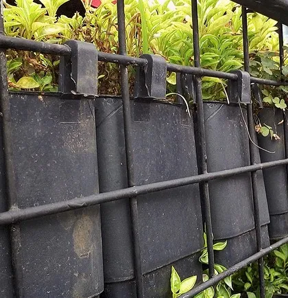 A close-up of the mesh panel system. The individual planters hook directly onto the grid, allowing for flexible designs and easy maintenance or replacement of plants.
