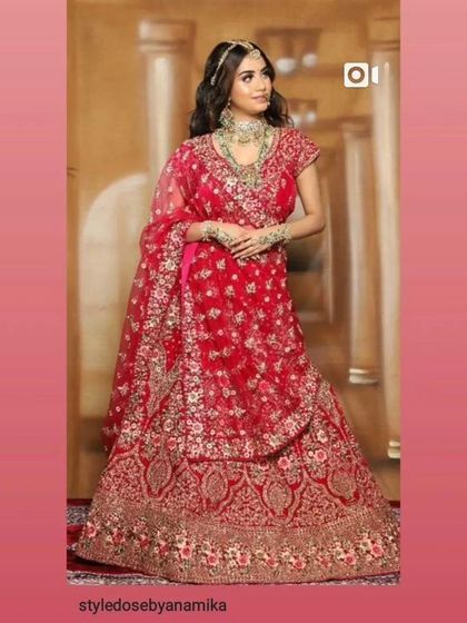 A full-length shot of a bride in a beautiful red lehenga with gold embroidery. A timeless and elegant choice available for rent.
