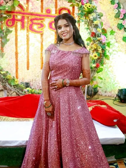 A happy client at her Mehendi ceremony in a sparkling pink gown. The off-shoulder design with fringe details is fun and festive.