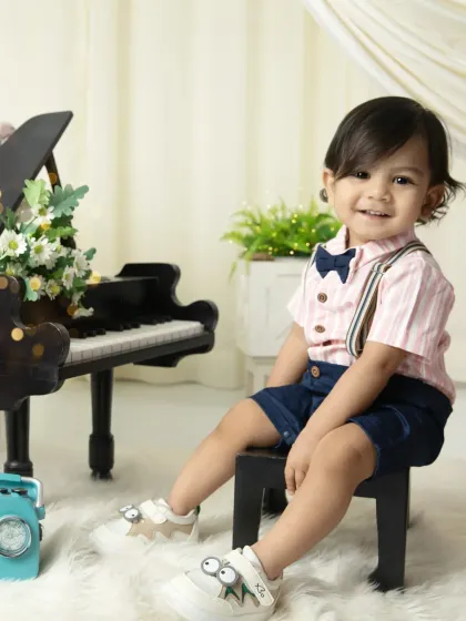 A tiny musician in the making. This creative milestone session features a miniature piano and a classic outfit, perfect for capturing your little boy's dapper personality and curious spirit in a timeless setting.