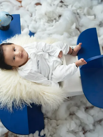 Ready for takeoff. This little pilot is sitting in a propeller plane, flying through a sky of fluffy clouds. It's a perfect theme for an adventurous little one.
