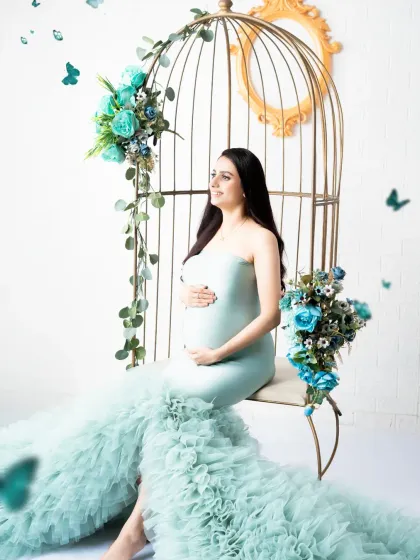A fairytale portrait with a flowing mint green gown and magical butterflies. The birdcage chair adds a touch of whimsical elegance to the scene.