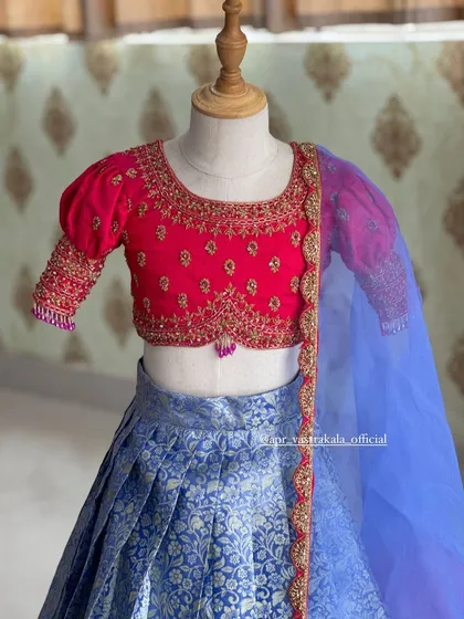 A close-up of the pink blouse, detailed with delicate gold embroidery around the neckline and on the puff sleeves.