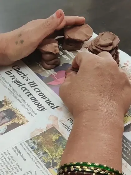 Two hands gently press down on small clay forms. This image shows the quiet, focused nature of my clay therapy sessions for seniors, where the process is more important than the final product.