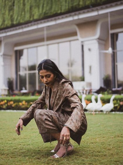 Anasuya Sengupta in a moment of quiet contemplation in a garden, with geese in the background adding a touch of unexpected life.