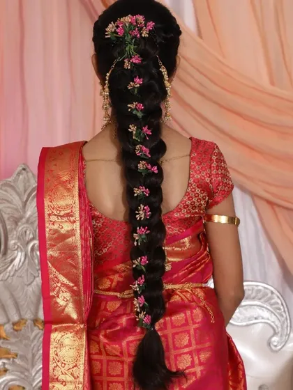 A classic South Indian braid for a puberty ceremony. I used delicate pink floral accessories along the length of the braid to match her beautiful red and gold saree.