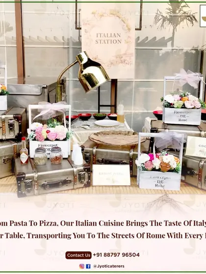 A charming Italian station setup with vintage suitcases and floral baskets. This station brings the taste of Italy to your event, from fresh pasta to gourmet pizzas.