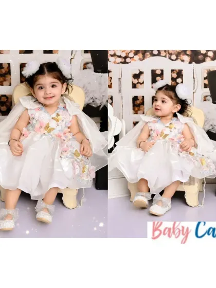 A little angel in her butterfly-themed party dress. This white gown features delicate 3D butterflies and a beautiful cape, making it a whimsical and elegant choice for a birthday or special event.