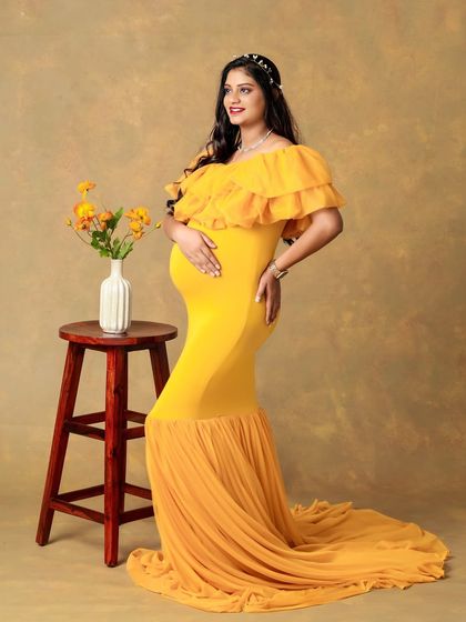 A vibrant and glowing portrait of a mom-to-be in a bright yellow gown. The color makes her stand out beautifully, and the mermaid-style dress accentuates her bump.
