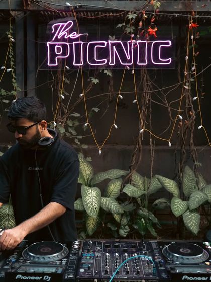 Behind the decks at "The Picnic", surrounded by greenery and good vibes. These daytime parties are a refreshing change from the dark club scene.