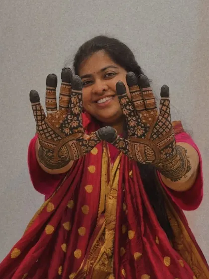 A lovely shot of a wedding guest proudly presenting her detailed henna art.