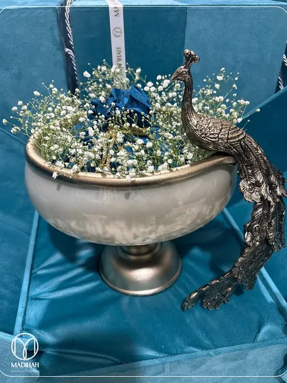 A detailed shot of the Peacock Bowl nestled in its blue gift box, surrounded by baby's breath. This is a gift that speaks of sophistication and thoughtfulness.