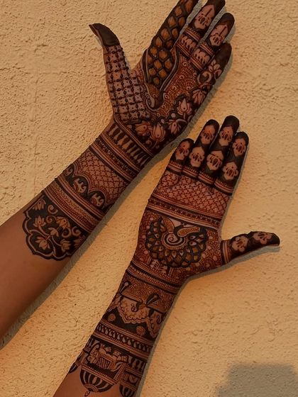 This design features a mix of peacocks, floral vines, and geometric check patterns, extending up the arm.