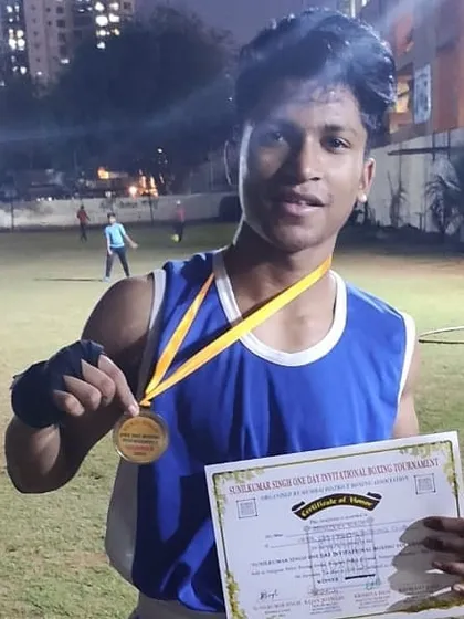 A young champion proudly displaying his gold medal and certificate of victory. These early successes build the confidence needed for a long career in boxing.