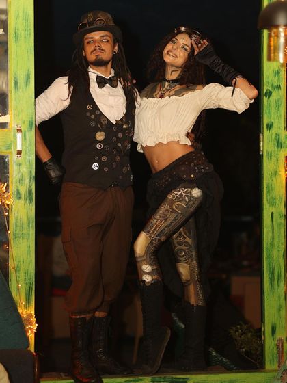 A full-length shot of the Steampunk couple, showing off the detailed costumes from head to toe, including custom-painted leggings and intricate vests.