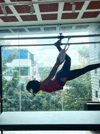 Embrace the challenge. This client works on her flexibility and strength with this hanging pose on the Cadillac.