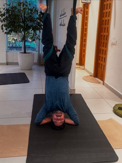 An inversion pose using the aerial hammock, which helps decompress the spine and improve circulation. This student demonstrates strength and trust as he comfortably hangs upside down.