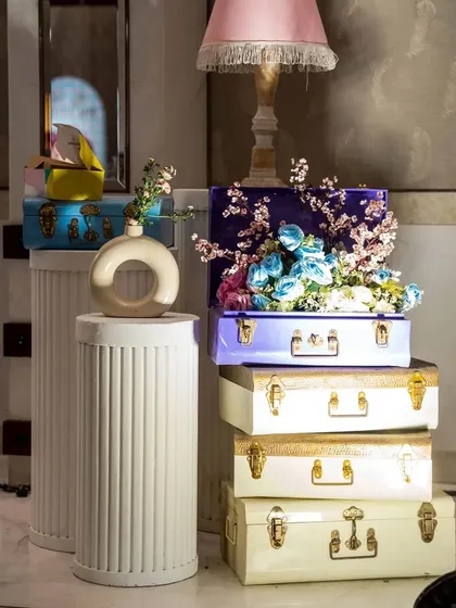 Vintage-style trunks in pastel colors, stacked and filled with flowers, create a chic and thematic decor accent. These details help build a rich, layered look.