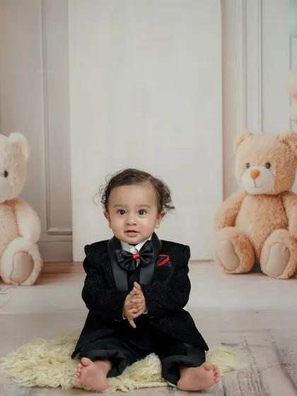 Dressed in a sharp tuxedo, this little man is the star of his first birthday shoot. The soft, neutral-toned balloons and teddy bears create a classic and elegant backdrop.