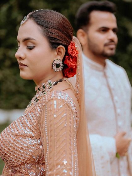 A close-up portrait of the bride with her eyes closed, her serene expression and the red roses in her hair creating a romantic and peaceful image.