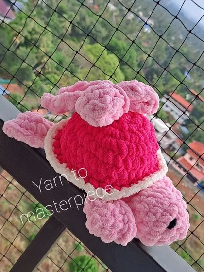 A plush turtle with a bow on its shell, photographed outdoors.