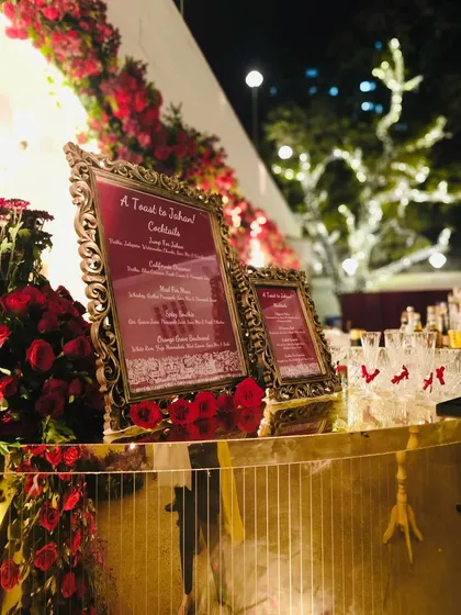 A beautiful evening shot of our gilded bar setup, adorned with red roses and ornate, custom-framed menus. The warm lighting and reflections on the mirrored surface created an inviting and glamorous focal point for the celebration.