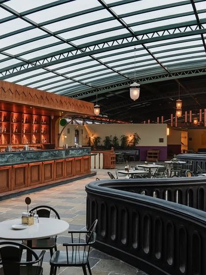 The view from a corner table on the mezzanine, showcasing the bar and the curved balustrade. This perspective highlights the multi-level layout I designed to create distinct zones and experiences within the large space.