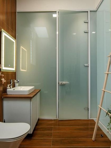 This bathroom combines wood-look wall tiles with a concrete-finish accent wall. A decorative ladder for towels adds a touch of rustic charm to the modern space.