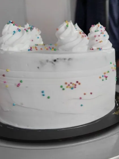 A full view of the eggless chocolate cake made using the Bakescape premix. It's decorated simply with white frosting and colorful sprinkles.