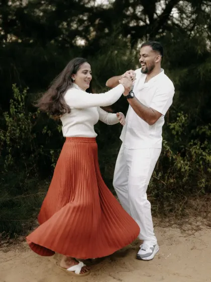 A couple dances joyfully, their movements creating a sense of freedom and happiness in this candid pre-wedding shot.