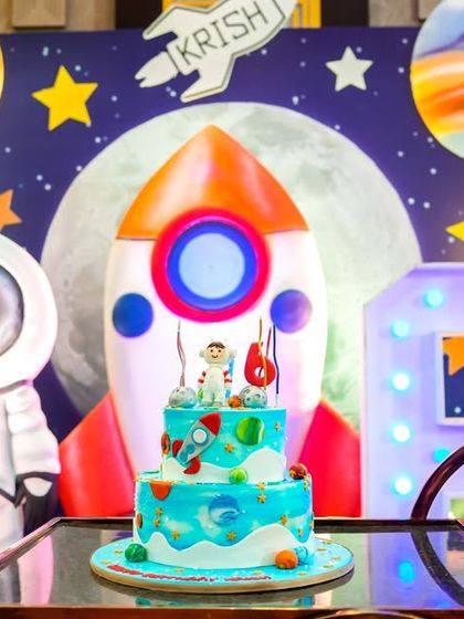 A custom space-themed birthday cake placed in front of the main stage backdrop.