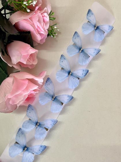 This soft blue fabric butterfly is perfect for a daytime event, adding a touch of serene beauty to your look.