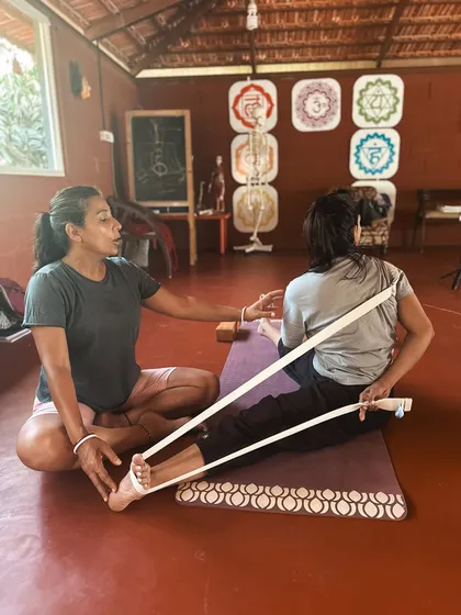 A student learns to use a strap to assist with a seated forward fold. This is part of our curriculum on adapting yoga for different levels of flexibility and addressing common issues like tight hamstrings.