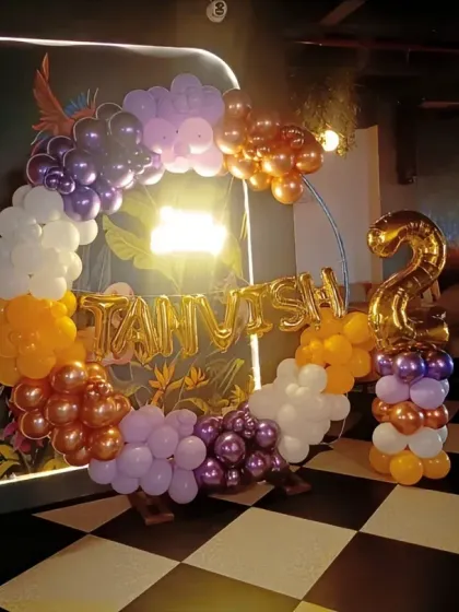 A multi-colored balloon ring in a dimly lit venue for a second birthday party.