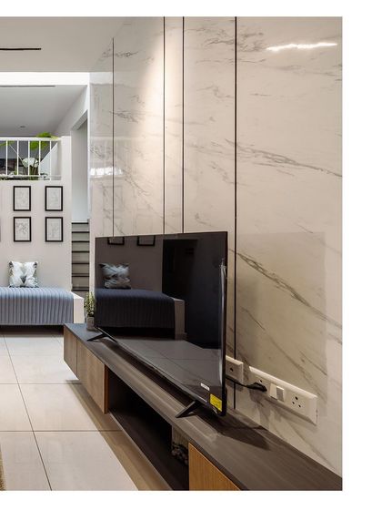 A view of a modern entertainment unit against a white marble-paneled wall. This image showcases the sleek, minimalist design and the effective use of materials in the space.