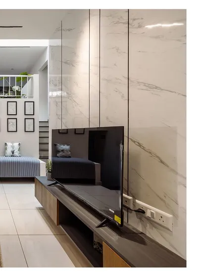 A view of a modern entertainment unit against a white marble-paneled wall. This image showcases the sleek, minimalist design and the effective use of materials in the space.